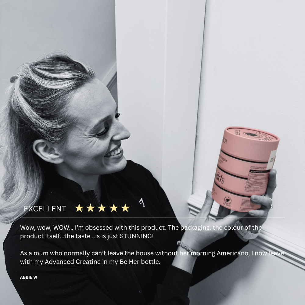 Customer holding a She Builds creatine tub, with her 5-star review