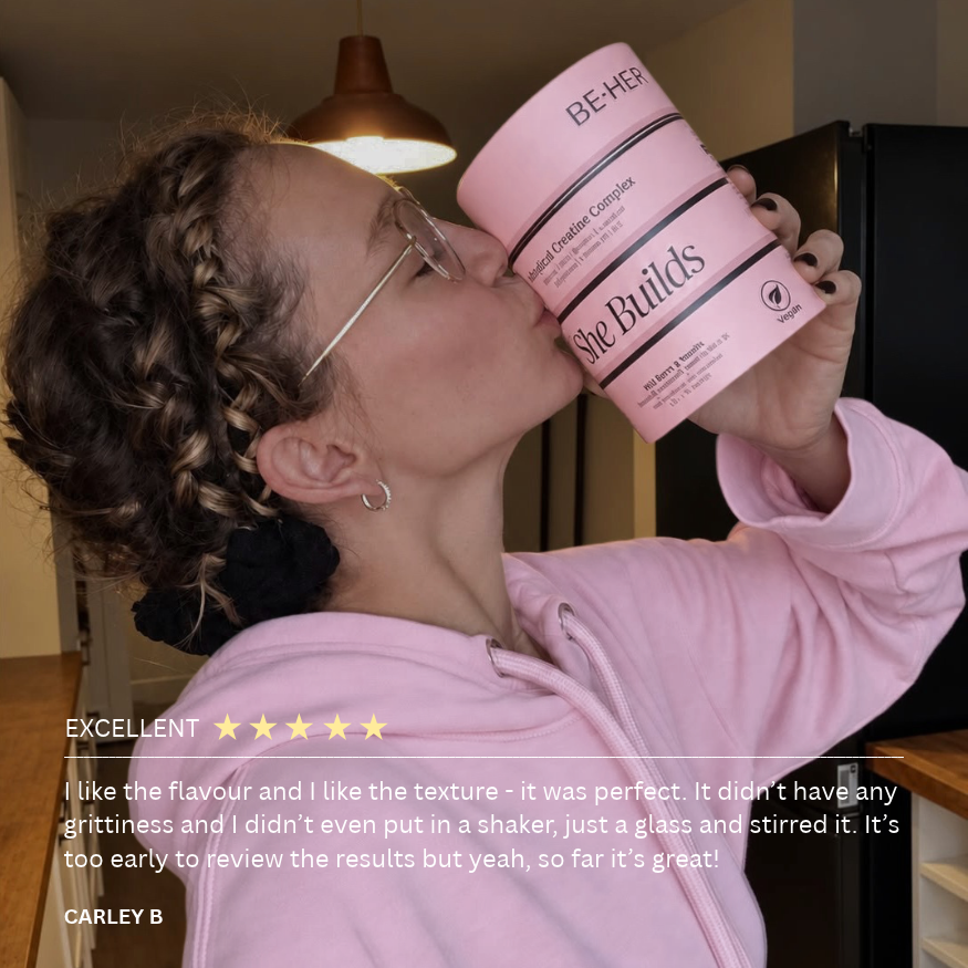 Customer raising a stack of She Builds creatine tubs to her face, with her 5-star review